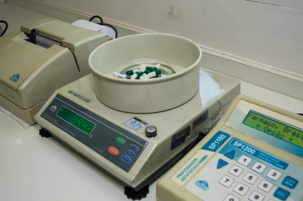 Balança de precisão e cápsulas no laboratório da Poção Mágica